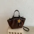 Detailansicht einer stilvollen braunen Wildleder Damentasche mit Blumenanhänger als Umhängetasche. - Ohne Anhänger / Kaffeebraun