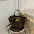 Braune Wildleder-Tasche im Detail mit süßem Blumen-Anhänger und praktischen Henkeln. - Ohne Anhänger / Grün