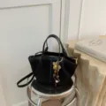Black bucket bag detail view featuring chic floral charm and metal hardware for women. - Black
