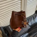 Detailansicht der braunen Wildleder-Beuteltasche mit schickem Kleeblatt-Anhänger und Kordel. - Mit Anhänger / Kaffeebraun