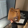 Braune Wildleder-Beuteltasche mit Tunnelzug und Blumenanhänger für modebewusste Damen. - Mit Anhänger / Braun