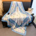 Detailed view of large floral and cute rabbit print silk scarf draped on sofa. - 130x130cm / Blue