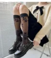 Vue détaillée de chaussettes noires transparentes à fleurs avec un design floral élégant. - Noir