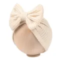 Close-up detail shot of the cute beige knitted baby hat featuring a large decorative bow on top. - Beige