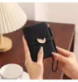 Close-up detail of a minimalist black short wallet with gold leaf buckle and wrist strap. - Black