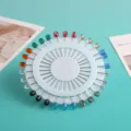 Bunte Kristall-Kopftuchnadeln auf weißem runden Halter, ideal für ethnische Mode und Dekoration. - Säulen-Bohrstil