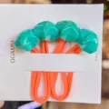 Colorful faceted star hair ties detail shot, vibrant fluorescent green stars with orange rubber bands for kids. - Lake Green