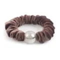 Detailed shot of brown velvet hair scrunchie featuring a glowing glitter decorative bead accent. - Tan