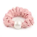 Detailed shot of a pink scrunchie featuring a large elegant faux pearl decoration charm. - Pink