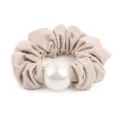 Detail shot of the crinkled beige honeycomb fabric scrunchie featuring a large central white pearl. - Khaki