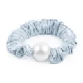 Gros plan detail d'un chouchou en satin bleu clair avec une grande perle artificielle. - Bleu