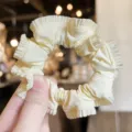 Pale yellow satin ruffled hair scrunchie detail view, sweet cute hair tie accessory. - Beige