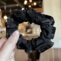 Black satin scrunchie detail view, elegant ruffled hair tie for women and girls daily styling. - Black