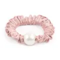Gros plan détaillé sur le magnifique chouchou en satin rose orné d'une grande perle blanche. - Rose foncé