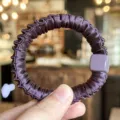 Detail view of a stylish dark purple small hair scrunchie featuring a chic square charm. - Deep purple