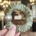 Detail of satin hair scrunchie with large metallic grey pearl accent, elegant hair tie. - Green