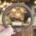 Close-up detail shot of brown satin hair tie with cute heart charm, elegant daily accessory. - Light Coffee