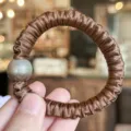 Detailed close-up of brown satin hair scrunchie with gradient pearl accent for women. - Caramel color