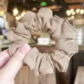 Close-up of beige linen texture scrunchie, soft fabric detail, elastic hair tie display. - Light Khaki