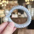 Close-up of double pearl hair tie, elegant satin wrapped elastic scrunchie detail shot. - Blue