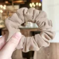 Primer plano detallado de un coletero para el pelo beige texturizado con tela plisada elástica. - Caqui Claro