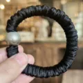 Vue de détail d'un chouchou en satin noir avec perle pour coiffure élégante de femme. - Noir