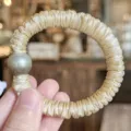 Vue détaillée d'un chouchou en satin champagne avec une décoration de perle grise. - Crème