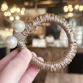 Gros plan detail de chouchou de cheveux en satin style coreen avec perles doublees. - Café Clair