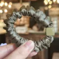 Vue détaillée d'un chouchou en satin vert foncé avec détail carré chic. Souple et élastique. - Vert Gris