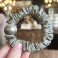 Satin scrunchie detail view with elegant pearl decoration, soft glossy fabric for daily hair styling. - Grey Green