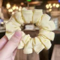 Detalle en primer plano de coletero amarillo texturizado, accesorio de pelo suave y elástico. - Amarillo leche