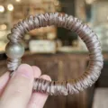 Gros plan d'un chouchou en satin avec une perle brillante, montrant la texture du tissu. - Couleur Thé au Lait