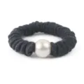 Closeup detail of a dark grey wool scrunchie featuring a large central white faux pearl. - Dark Gray