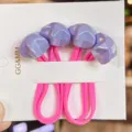 Close-up detail of cute pink elastic hair ties with purple faceted star ornaments on white card. - Purple