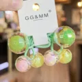 Primer plano detallado de coleteros coloridos de bola disco con cuentas y bandas verdes. - Verde