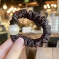 Closeup view of dark brown satin hair scrunchie with large white pearl detail accessory. - M / Dark Brown