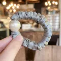 Close-up detail of grey satin hair scrunchie with large white pearl accent for styling. - M / Blue Gray