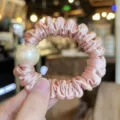 Detailed shot of pink satin hair scrunchie featuring a large elegant pearl decoration. - M / Deep Pink