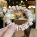 Close-up of elegant satin hair scrunchie with large pearl detail, perfect for hair. - M / Light Pink