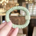 Close-up detail of light green scrunchie with matching square bead hair accessory. - Green