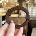 Primer plano de un coletero plisado marrón con abalorio cuadrado elegante, suave y elástico. - Marrón