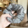 Detailed view of grey satin hair scrunchie, smooth fabric, puffy design for daily hair styling. - Gray