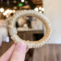 Nahaufnahme Detail des glatten Satin Haargummis mit eleganter Katzenaugen Steinperle. - Hautfarben