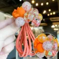 Détail de l'élastique à cheveux pour enfant avec perles pailletées et accessoire de dessin animé. - Orange