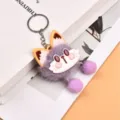 Plush fox keychain detail shot, featuring soft purple fur, cute cartoon face and dangling pom poms. - Purple
