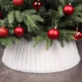 Vue détaillée de la jupe de sapin de Noël en peluche plissée blanche avec des boules. - Peluche Rayée Blanche