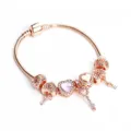 Rose gold charm bracelet detail showing intricate heart beads, dangling keys and pink crystal center. - Pink Heart (#5)