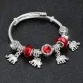 Primo piano di un braccialetto DIY in argento con ciondoli a forma di elefante e perle rosse. - Diametro 5.5cm / Argento