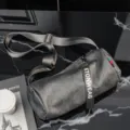 Detailed view of the gray cylindrical crossbody bag with adjustable strap and chic black pull. - Gray