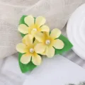 Detailed close-up of the lovely yellow artificial flower hairpin with pearls and green leaves. - Yellow